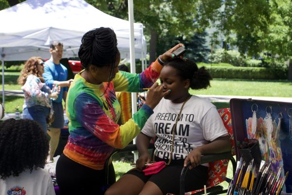 A person puts face paint on a child.