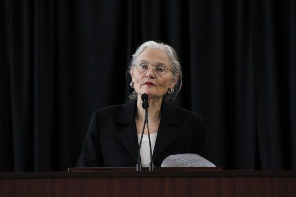 A person speaks at a podium in front of a black background.