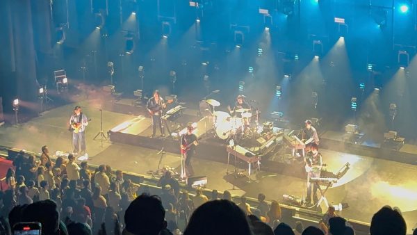 A person plays a guitar with a band behind him.