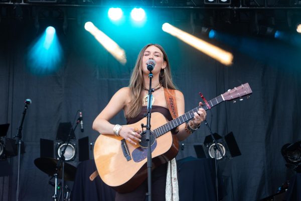 A person plays guitar on a stage with bright lights.