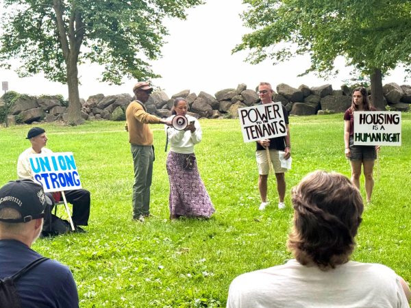 A person speaks into a megaphone as others hold protest signs.