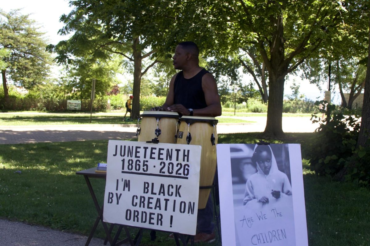 A person plays drums with a sign in front that reads “Juneteenth.”