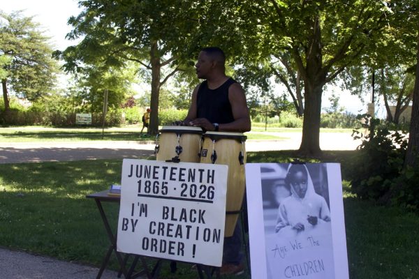 A person plays drums with a sign in front that reads &ldquo;Juneteenth.&rdquo;