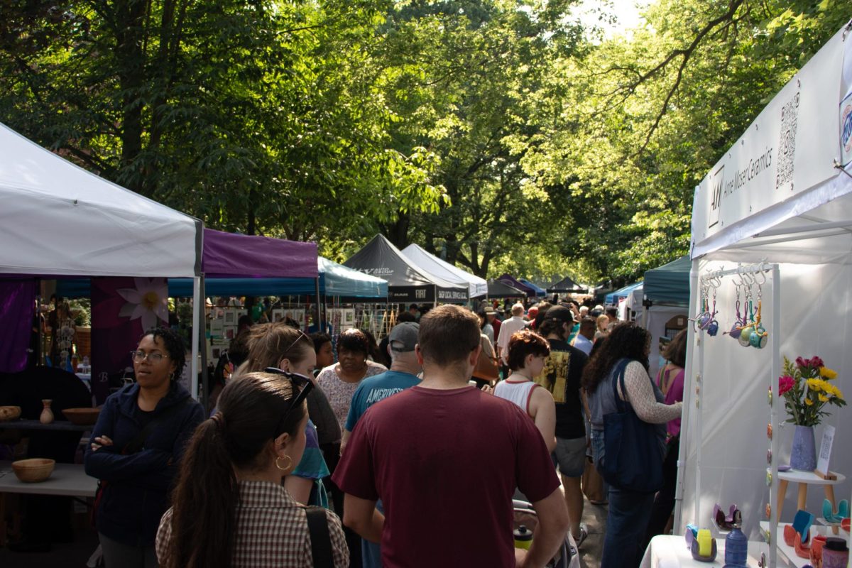 A crowd of people browse various vendor tents.