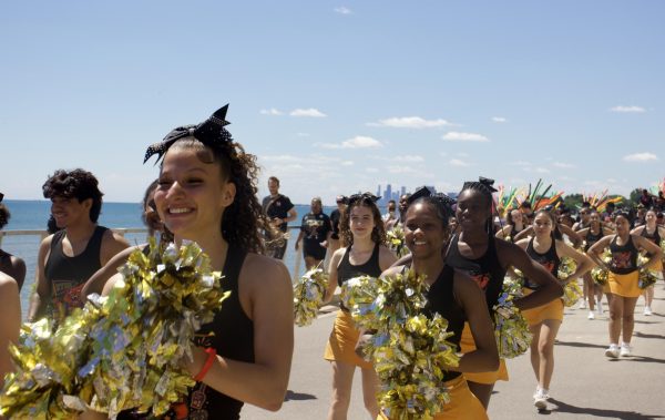 A group of people in cheerleading uniforms walk along a lakefront.