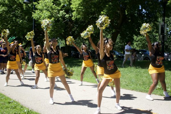 People with pompoms dance on a path.