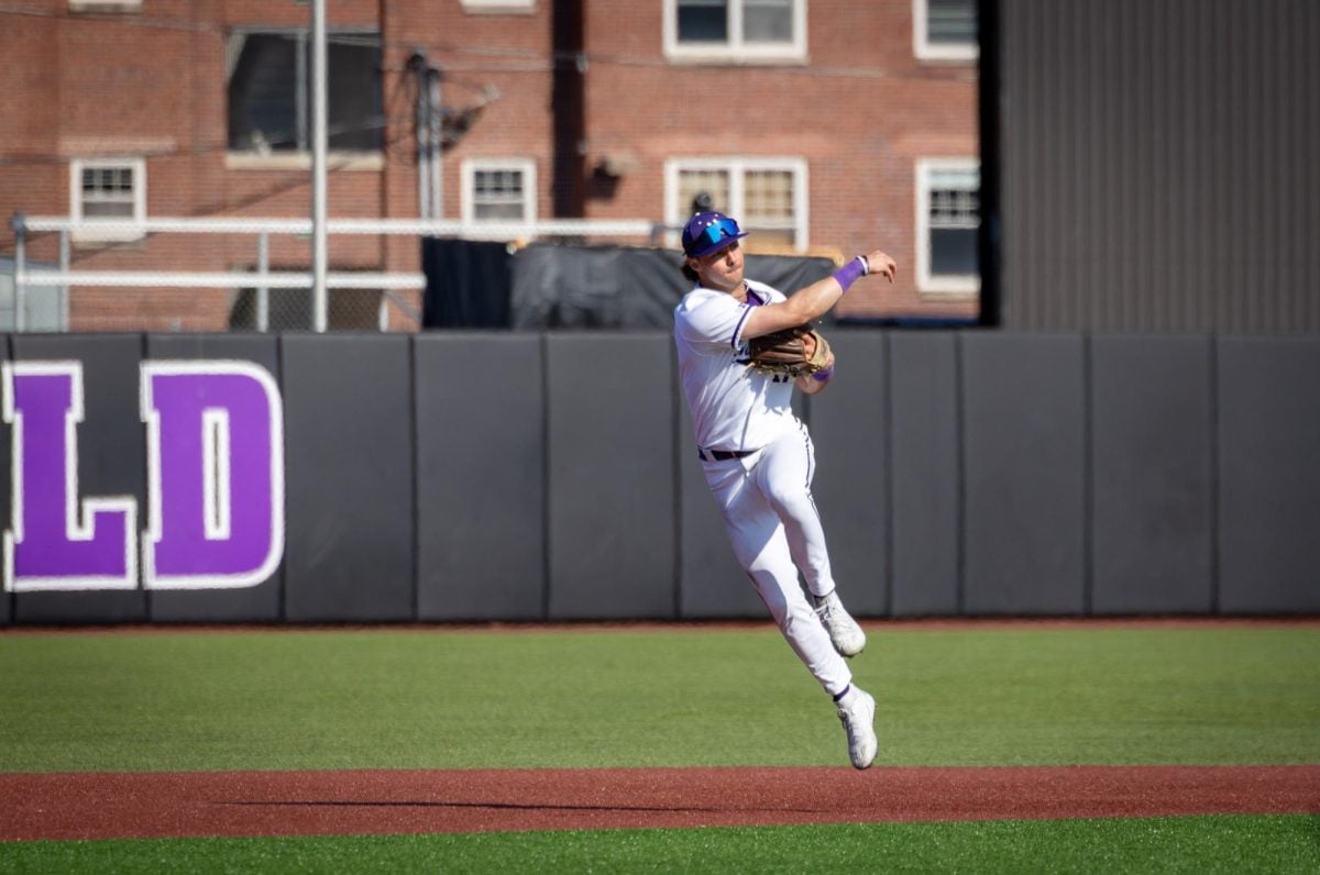 A player in a white jersey throws a ball to first base.