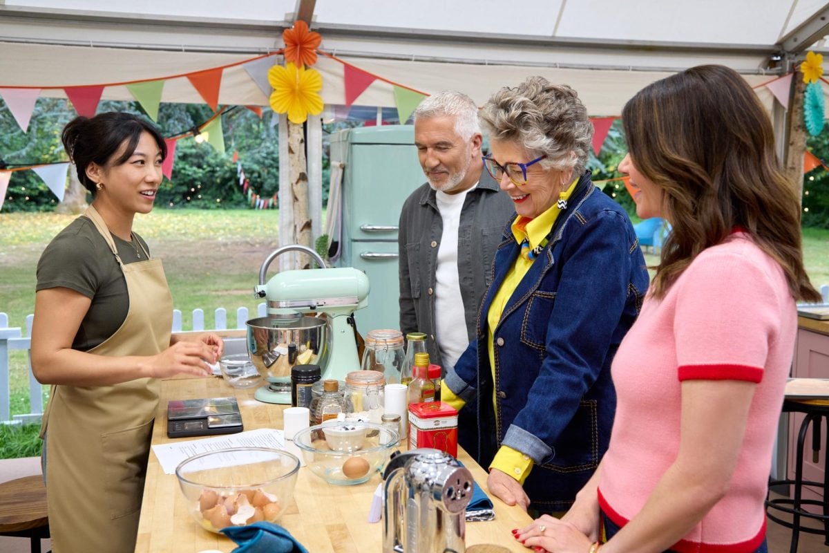 Four people stand around a table with baking supplies on it
