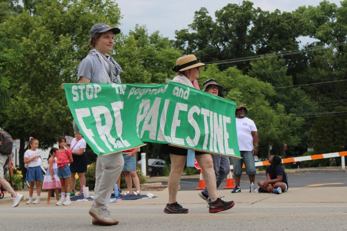 Three people holding a banner walk during a parade