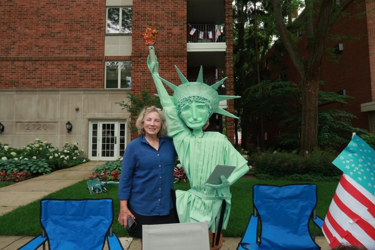 A parade attendee poses next to a replica of the Statue of Liberty