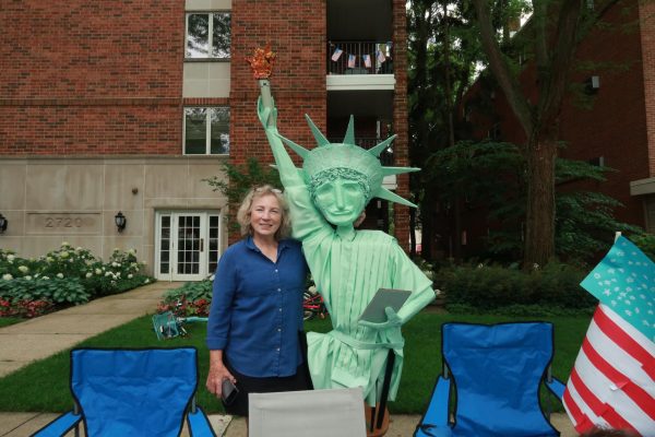 A parade attendee poses next to a replica of the Statue of Liberty