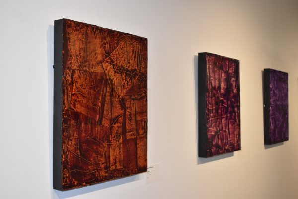An angled photo of three paintings on a wall.