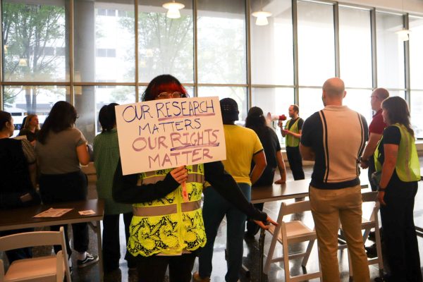 A person holds a sign that reads “OUR RESEARCH MATTERS, OUR RIGHTS MATTER.”