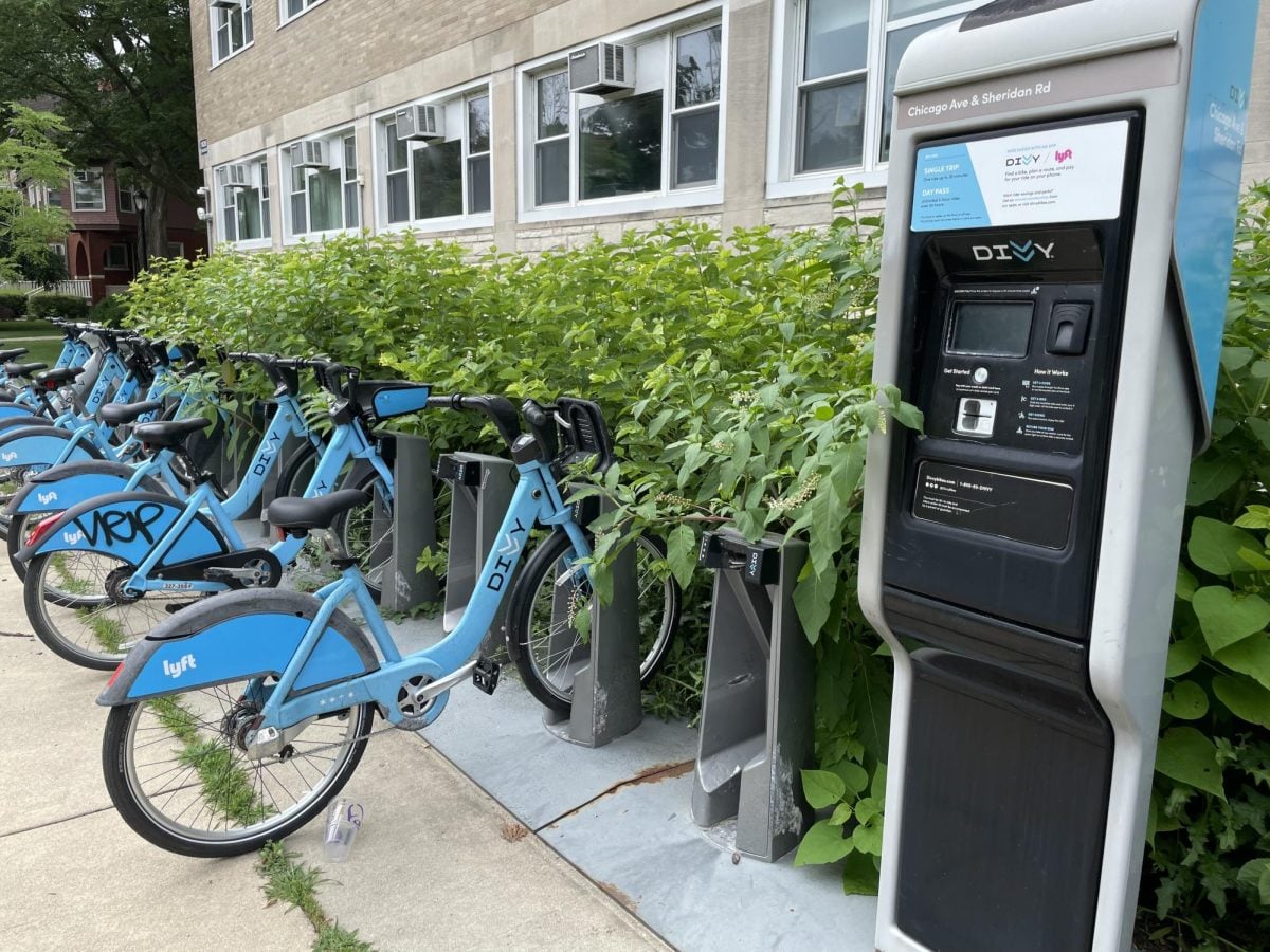 A Divvy bike station with parked blue bikes next to a bush