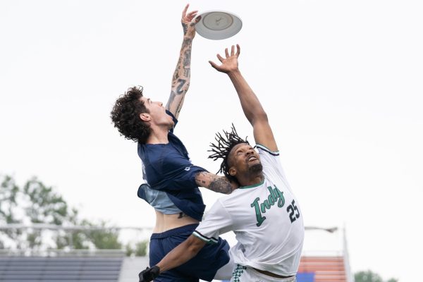 A player in blue and a player in white jump for a disk.