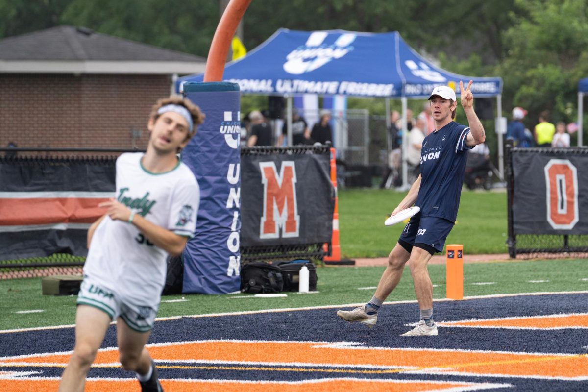 A player in blue holds up a peace sign toward an opposing player