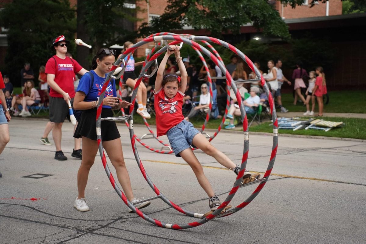 A person swings on a cyr wheel during the parade