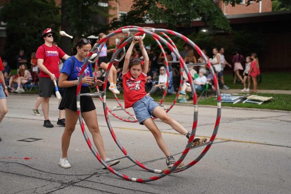 A person swings on a cyr wheel during the parade