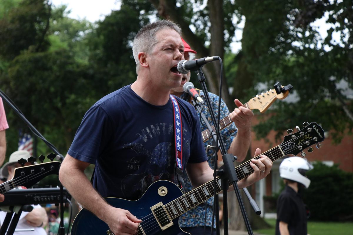 A person performs rock music with three bandmates