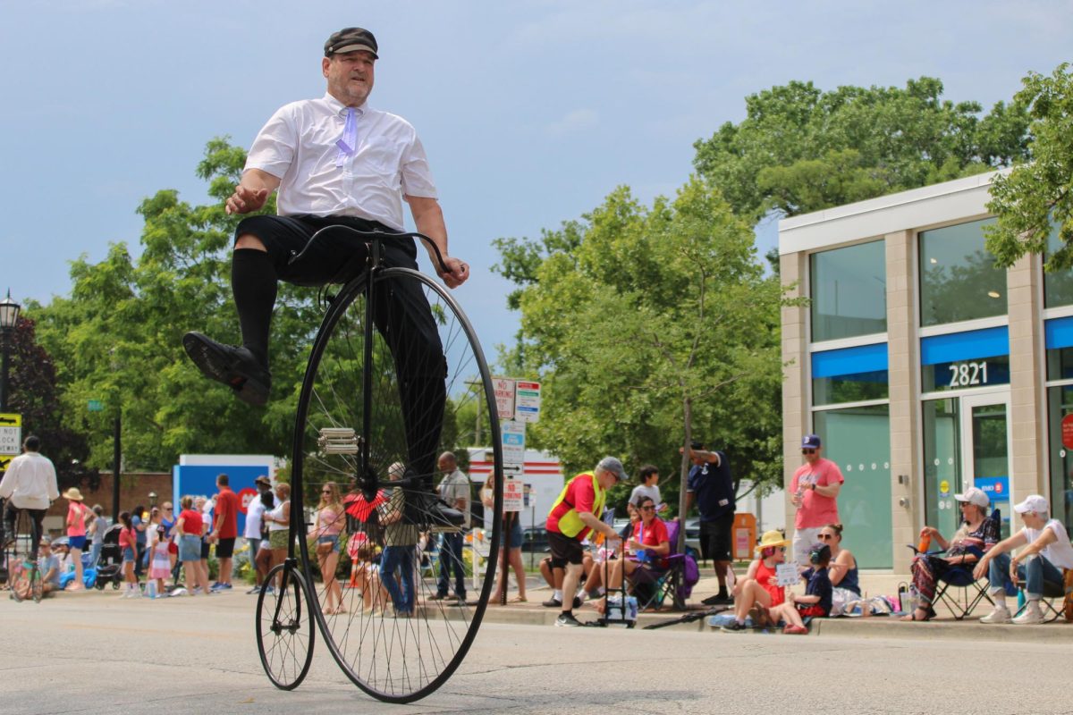 A person rides a penny-farthing bicycle down Central Street