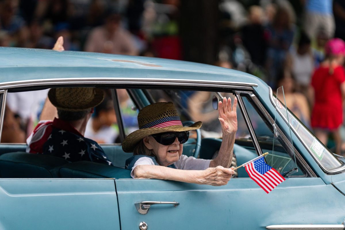 Two people wave to the crowd as they drive through the parade
