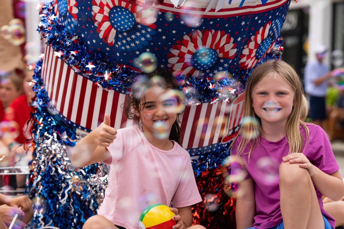 Two children smile as they ride on a float in the parade