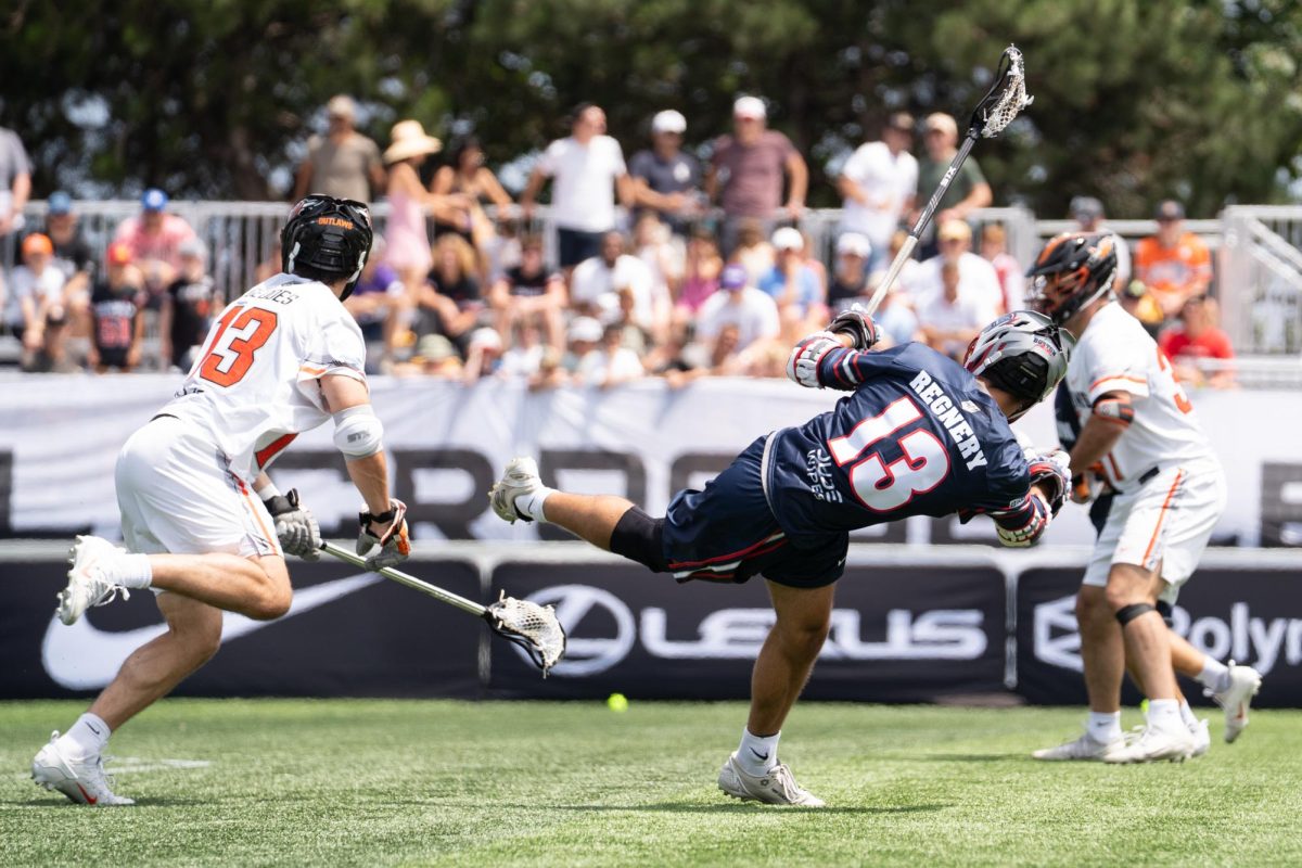 A player in a dark blue jersey falls backward after a shot.