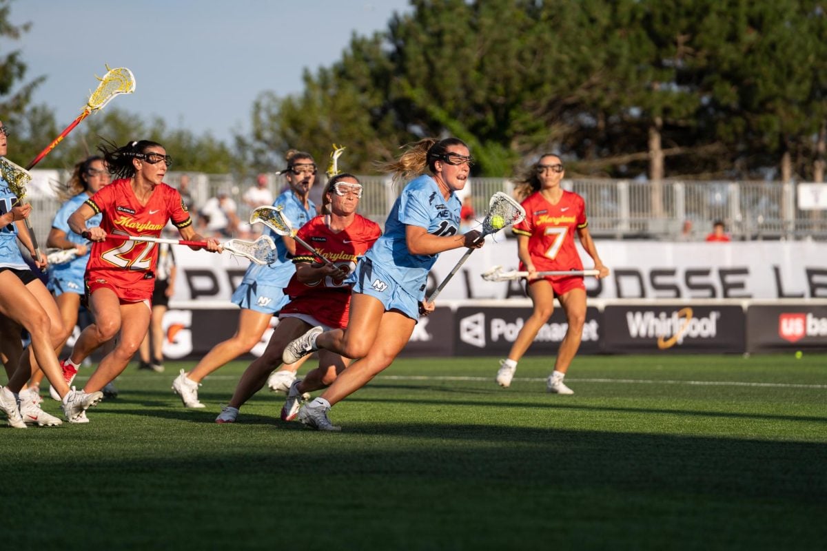 A player in a blue jersey runs with the ball away from defenders.