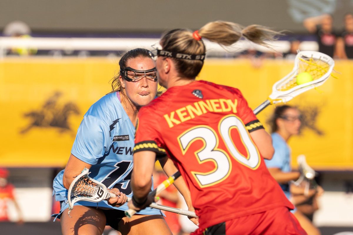 A player in a blue jersey stares down an opponent carrying the ball.