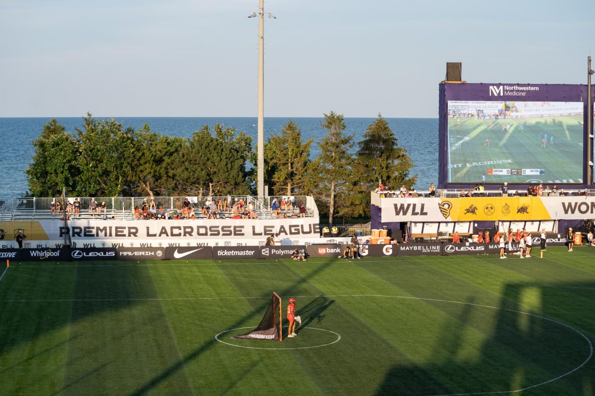 A wide shot of a lacrosse field and a lake. 