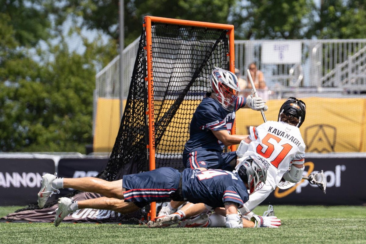 A player in a white jersey falls into the crease while attempting a shot. 